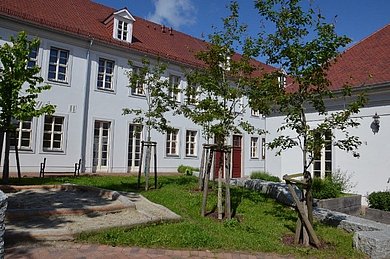 Hinterhof der Schule mit Bäumen und Sandkasten