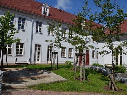 Hinterhof der Schule mit Bäumen und Sandkasten