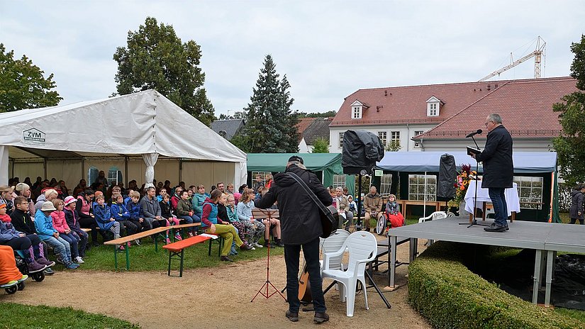 Schüler sitzen draußen auf Bänken bei einer Andacht