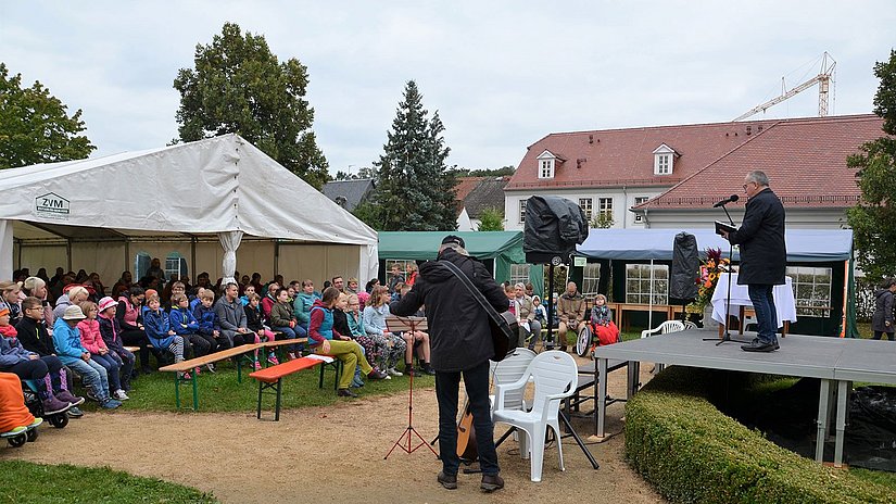 Schüler sitzen draußen auf Bänken bei einer Andacht