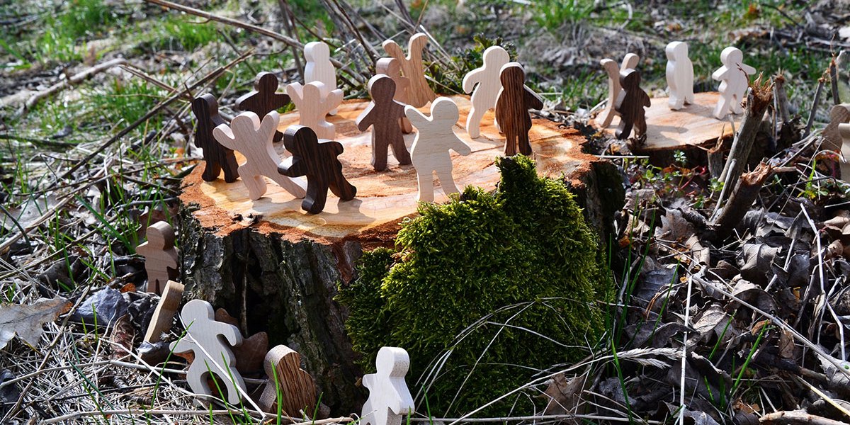 Viele Holzfiguren stehen auf einem Baumstumpf. Der Baum wurde frisch gefällt.